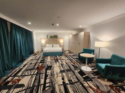 pokój hotelowy z łóżkiem i 2 krzesłami w obiekcie Helnan Royal w Dubaju