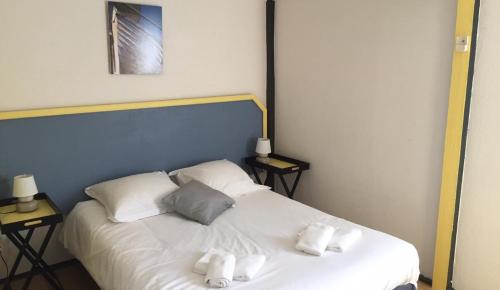 a bedroom with a white bed with two pillows at Hostellerie De La Source in Arles