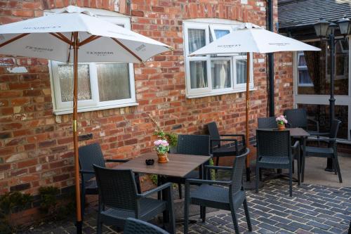 two tables and chairs with umbrellas on a patio at Millers Hotel by Greene King Inns in Sibson