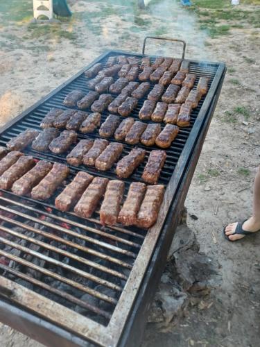 un montón de salchichas y donuts cocinando en una parrilla en Plaiul Cucului, en Tărcaia