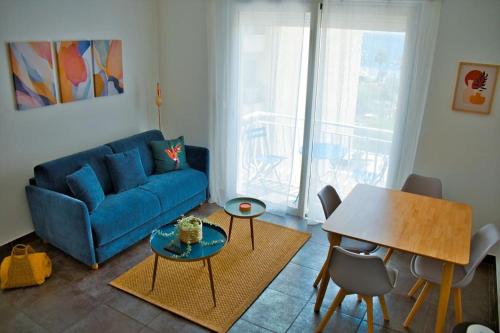 un salon avec un canapé bleu et une table dans l'établissement Cosy studio à 2 pas de la plage, à Nice