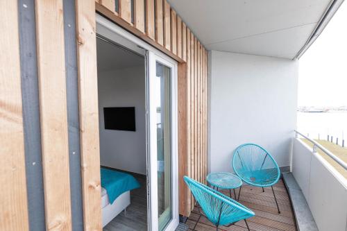 Zimmer mit einem Balkon mit einem Bett und einem Stuhl in der Unterkunft Katamaran in Olpenitz