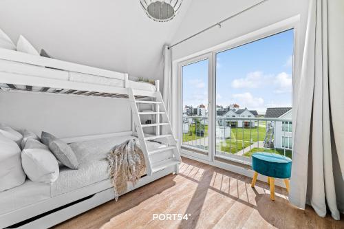 a bedroom with a white bed and a large window at Meerhaus 18 in Olpenitz