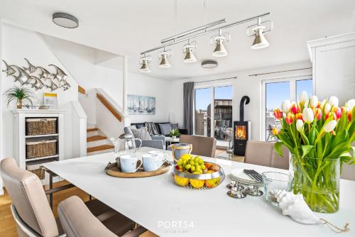 een keuken en een woonkamer met een witte tafel met een vaas met bloemen bij SeaDream in Olpenitz