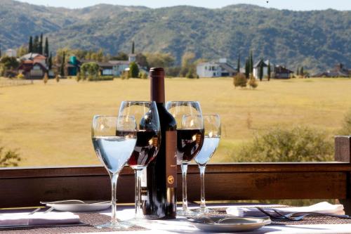 two glasses of wine sitting on a table with a bottle of wine at Ayres del Champaqui Hotel Boutique Experiencial & Spa in Villa General Belgrano