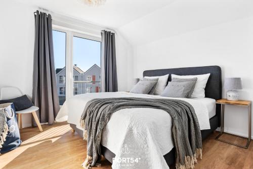 een witte slaapkamer met een bed en een groot raam bij Port Seven in Olpenitz