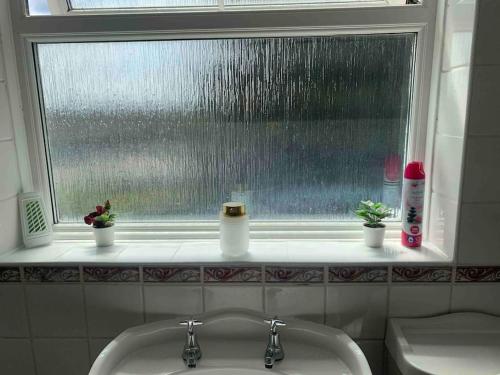 a bathroom sink with a window with rain on it at 3 Bedrooms spacious house in Calcot , Reading in Tilehurst