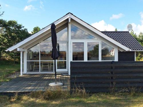 una casa con una sombrilla sentada en una cubierta en 6 person holiday home in Snedsted en Stenbjerg