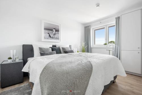 a white bedroom with a bed and a window at Marina Sunrise in Olpenitz