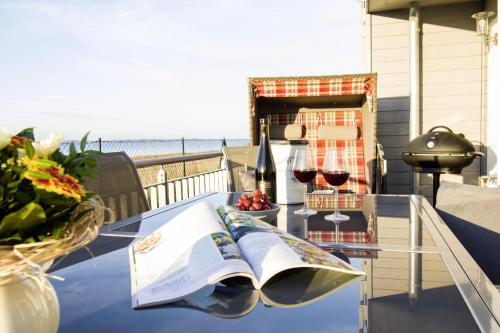 een tafel met een boek en wijnglazen op een balkon bij Heimathafen in Olpenitz