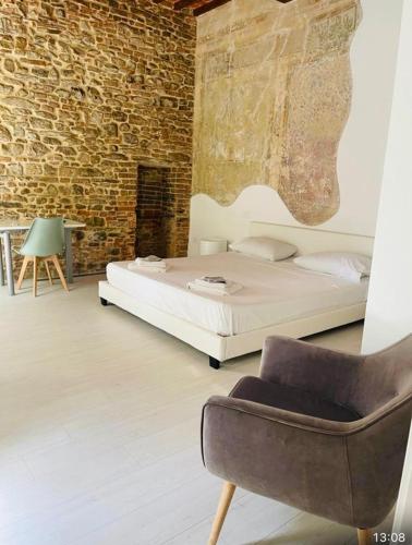 a bedroom with a bed and a chair and a brick wall at La Torre di Borgunto - Piazza Grande in Arezzo