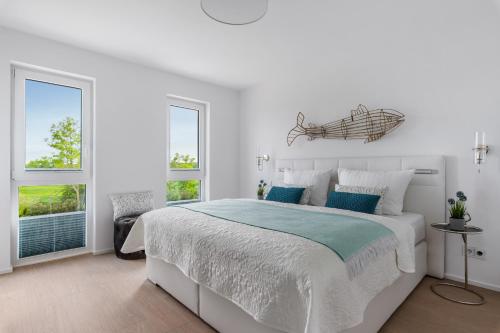 una camera bianca con un grande letto e due finestre di Ausguck 34 a Olpenitz