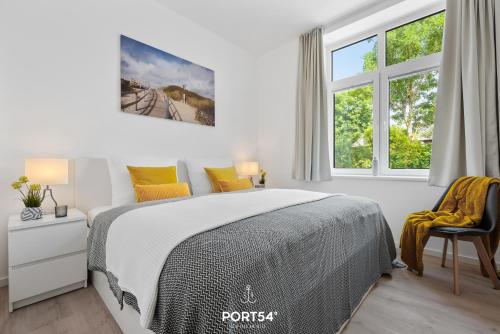 ein weißes Schlafzimmer mit einem Bett und einem Fenster in der Unterkunft Ferienwohnung Freigeist, App 16 Emmelsbüll in Emmelsbüll-Horsbüll