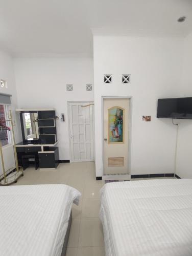 ein weißes Zimmer mit 2 Betten und einer Tür in der Unterkunft Griya Adevita Sidoarum in Sleman