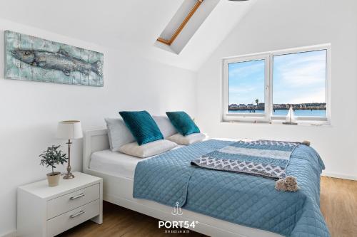 sypialnia z łóżkiem z niebieską kołdrą i oknem w obiekcie Sea Bay w mieście Olpenitz