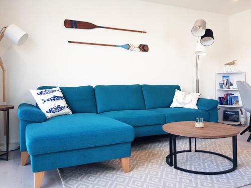 um sofá azul numa sala de estar com uma mesa em Ferienhaus Ostseesegler em Glücksburg
