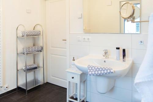a white bathroom with a sink and a mirror at Strandquartier Solitüde in Flensburg