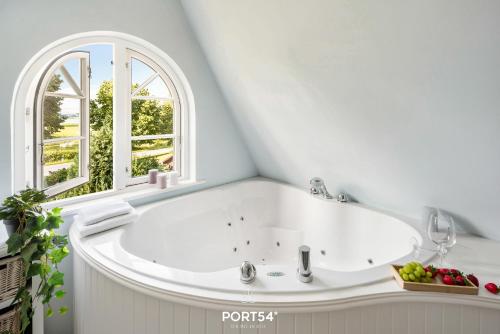 a white bath tub in a room with a window at Reethüs Schleiblick in Selk
