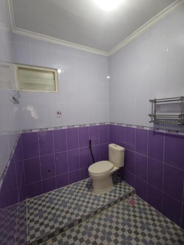 ein Bad mit WC und lila gefliesten Wänden in der Unterkunft Griya Adevita Sidoarum in Sleman