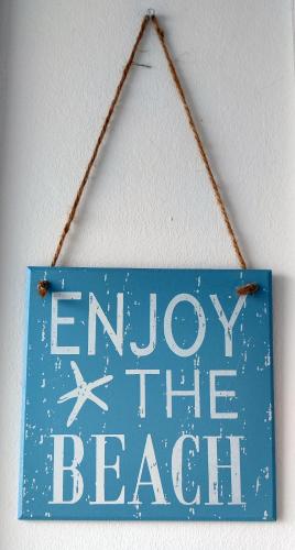 a sign that says enjoy the beach hanging on a wall at Ferienhaus Meerzeit Marina Wendtorf in Wendtorf
