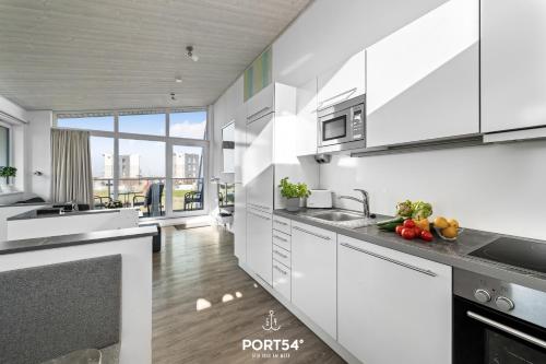 a kitchen with white cabinets and a large window at Ferienhaus Bottsand Marina Wendtorf in Wendtorf