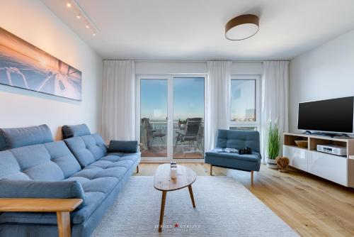 a living room with a blue couch and a tv at Marina Sunset West in Olpenitz