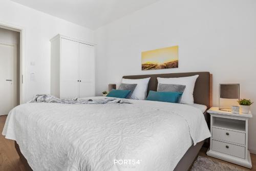 een witte slaapkamer met een groot bed met blauwe kussens bij Seewind in Olpenitz