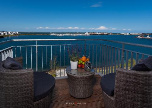 un balcone con sedie e un tavolo con vista sull'acqua di Hafenwelt a Olpenitz