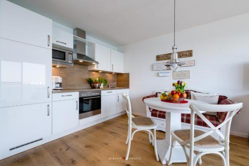a kitchen with white cabinets and a table with fruit on it at Seestern in Olpenitz