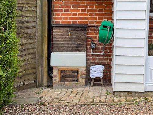 a sink and a chair next to a brick wall at Rose Cottage rural cosiness with footpaths to the local Macro Brewery Pub in Edwardstone
