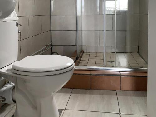 a bathroom with a toilet and a shower at Kingsworth inn Port Elizabeth in Port Elizabeth