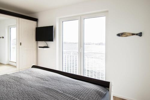 ein Schlafzimmer mit einem Bett und einem großen Fenster in der Unterkunft Meeresmelodie in Olpenitz