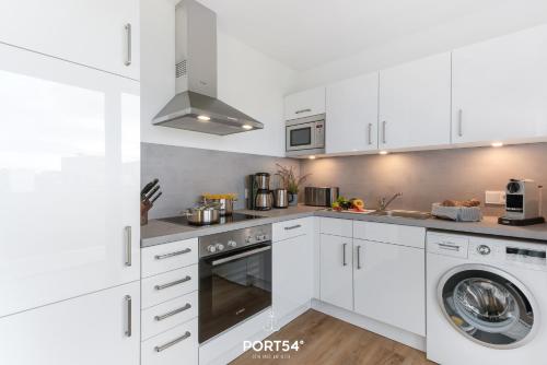 una cucina con mobili bianchi, lavatrice e asciugatrice di Weisse Düne II a Olpenitz