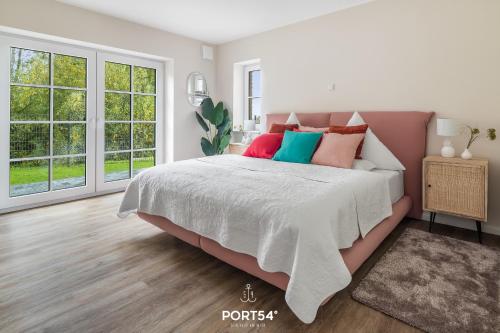 a white bedroom with a large bed with colorful pillows at Flamingo Bay in Osterhever