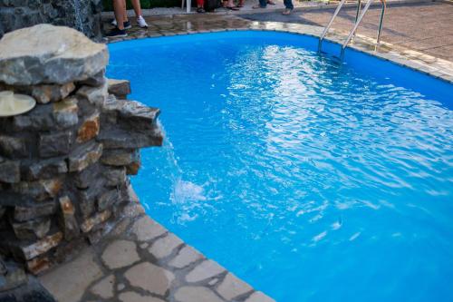 a pool with blue water and a stone wall at Resort La Familia in Bihać