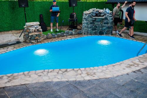 two men standing next to a blue swimming pool at Resort La Familia in Bihać