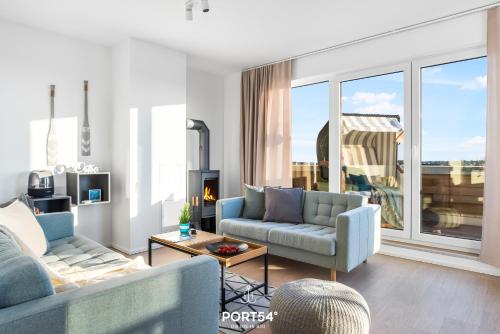 ein Wohnzimmer mit zwei blauen Sofas und einem großen Fenster in der Unterkunft Strand Loft in Olpenitz