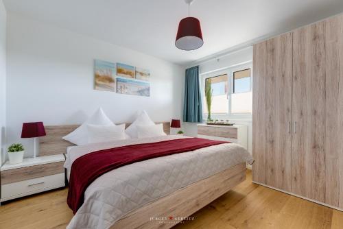 a white bedroom with a large bed and a window at Marinablick in Olpenitz