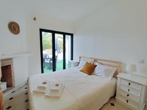 ein Schlafzimmer mit einem weißen Bett mit zwei Tabletts drauf in der Unterkunft Aldeamento Praia dos Beijinhos in Porches