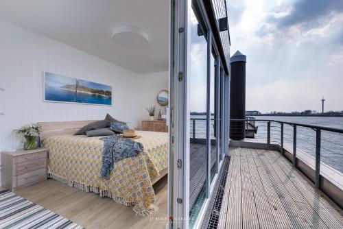 a bedroom on a boat with a bed on a balcony at Tokai in Olpenitz