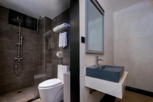 ein Badezimmer mit einem Waschbecken, einem WC und einem Spiegel in der Unterkunft Garden Villa Resort Yangshuo in Yangshuo