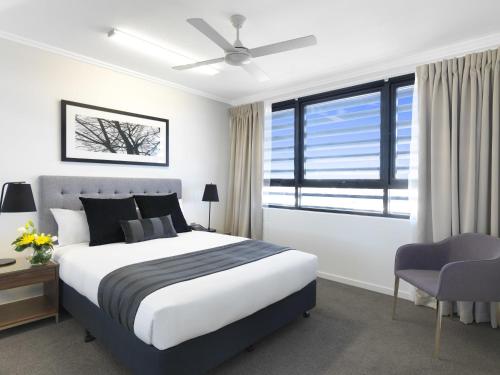 a bedroom with a bed and a ceiling fan at Oaks Mackay Carlyle Suites in Mackay