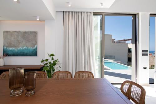 a dining room with a table and a view of a pool at Villa Manu Luxury Living in Stalos