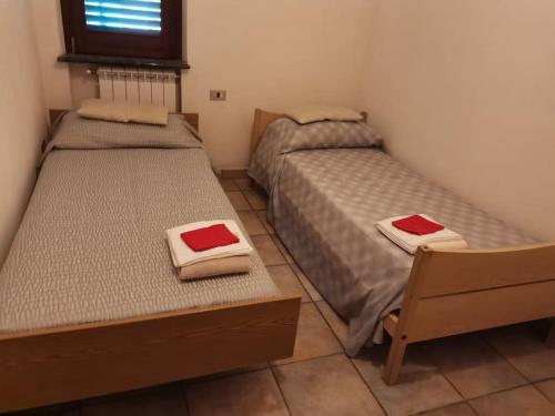 Dos camas en una habitación pequeña con toallas rojas. en Appartamento "Il Glicine", en Torraca