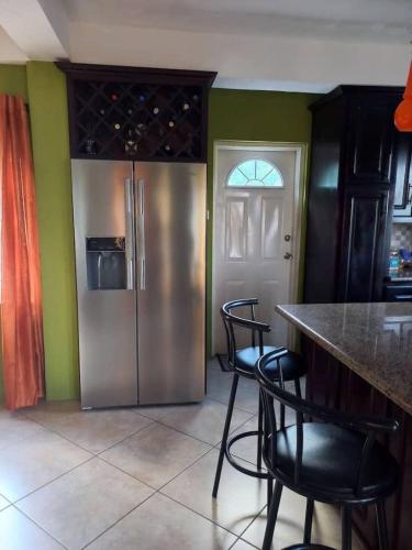 a kitchen with a stainless steel refrigerator and black chairs at BelleAir Views in Gros Islet