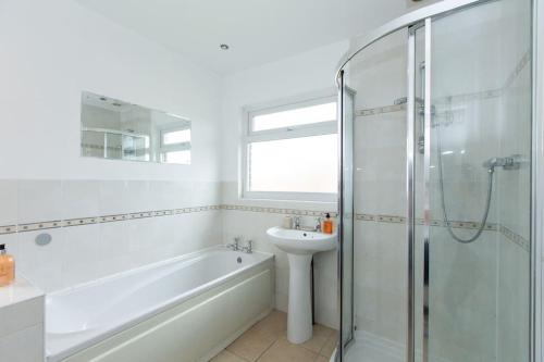 La salle de bains blanche est pourvue d'un lavabo et d'une douche. dans l'établissement Charming 3-Bed Retreat, Excellent Locaton, à Nottingham
