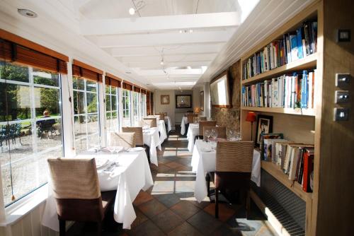 a restaurant with tables and chairs and books at Monachyle Mhor Hotel in Lochearnhead