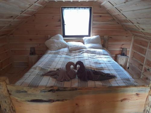 a bed in a log cabin with two swans on it at Glamping pod hradem in Česká Kamenice