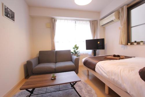 Un dormitorio con una cama, un sofá y un televisor. en LUANA in BELUBEE, en Tokio
