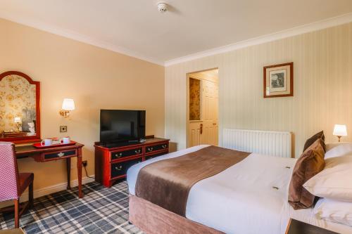 a hotel room with a bed and a desk and a television at Muthu Belstead Brook Hotel in Ipswich